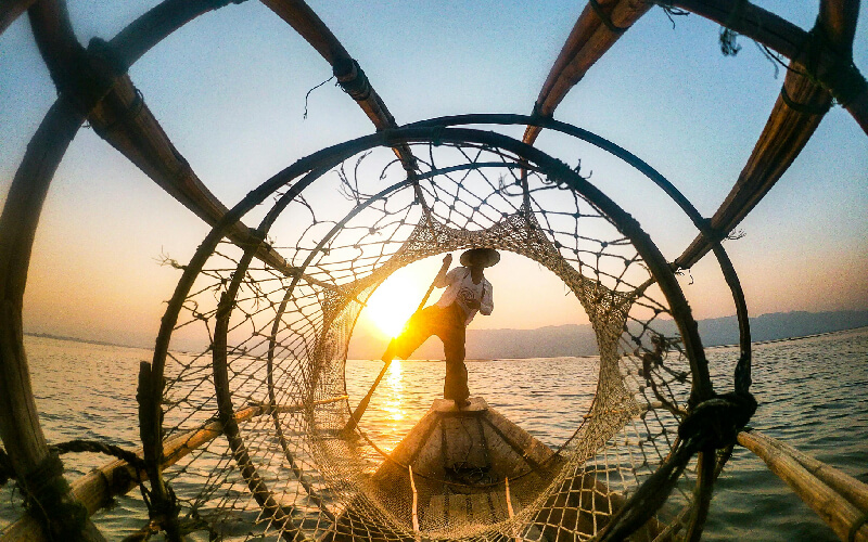 Man Standing On Boat During Sunrise in Myanmar - south east asia tours